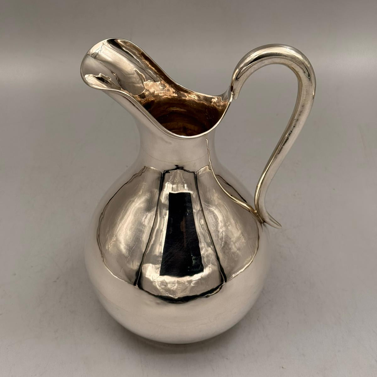 Detail of the graceful curved handle on the smooth silver pitcher by PNR Decor ship from USA