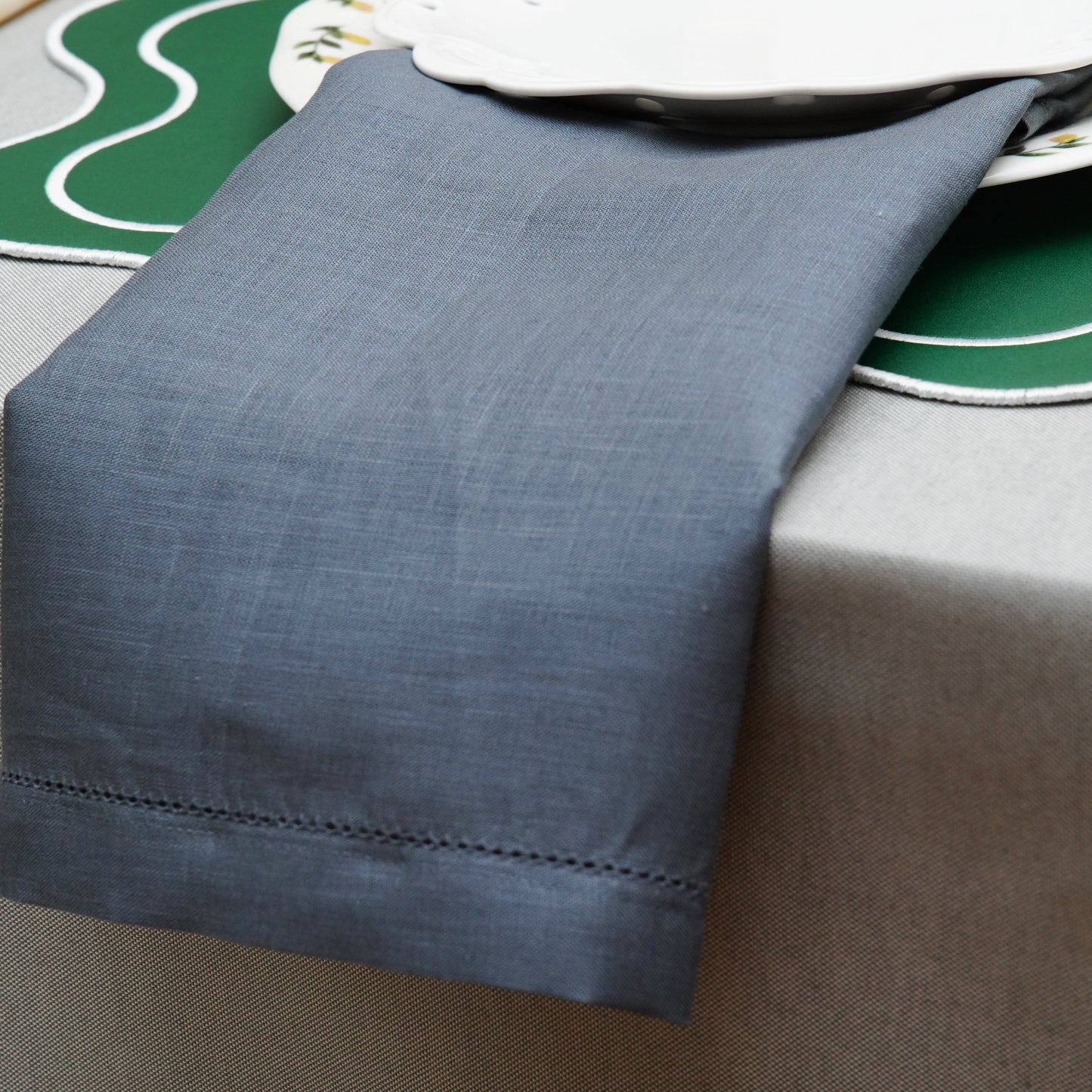 Gray table linen draped over the table edge, highlighting the neat hem and textured weave.