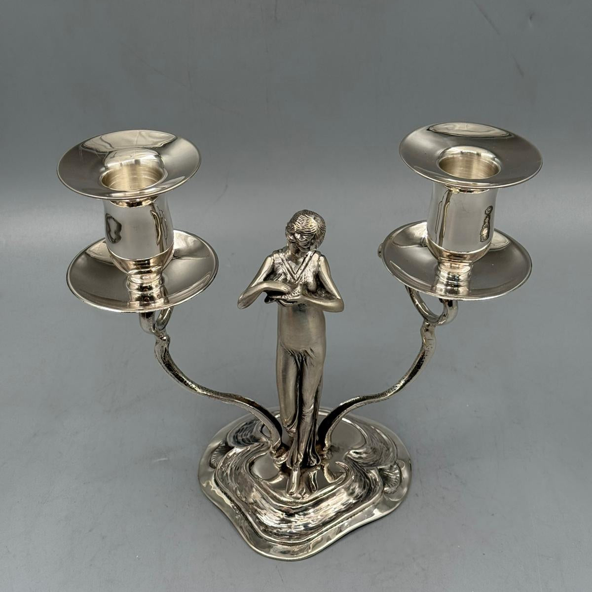 Silver double-arm candlestick with an elegant woman figure holding two candle holders.