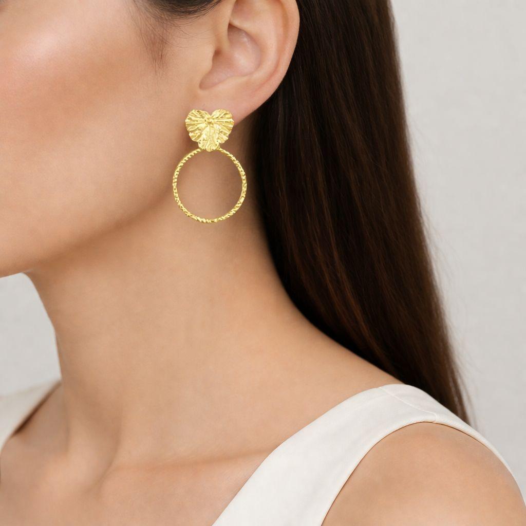 Close-up view of organic geranium leaf hoop earrings, a unique botanical jewelry design. These gold plated silver statement earrings show intricate leaf veining and a refined textured hoop.