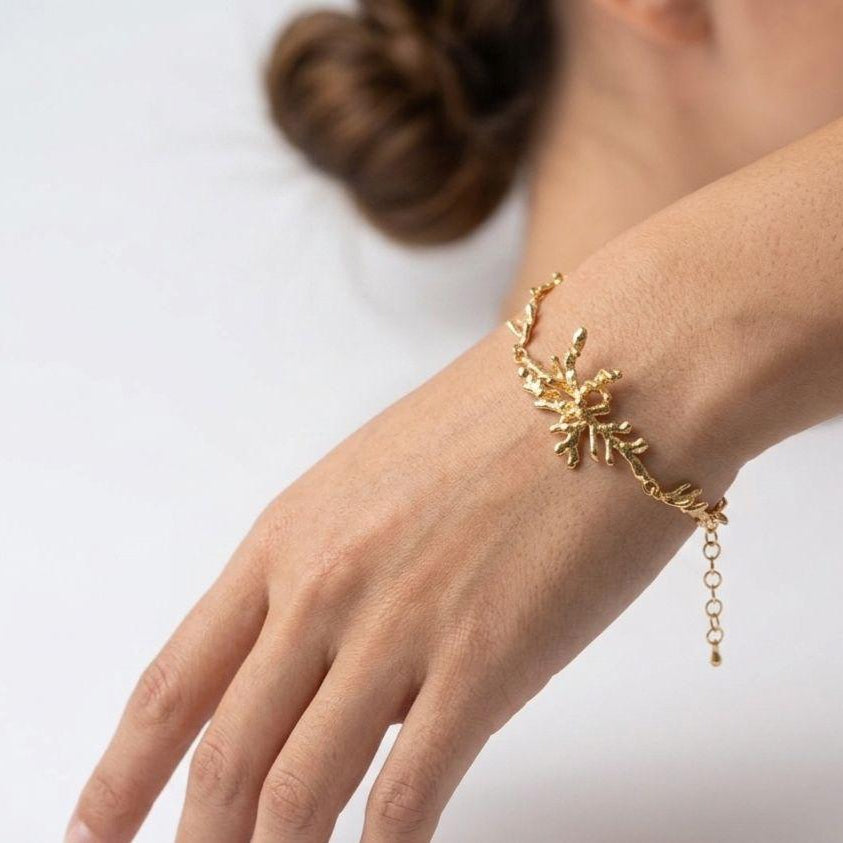 A handcrafted 18K gold-plated 925 sterling silver bracelet featuring an organic, layered pine branch centerpiece and botanical chain links.