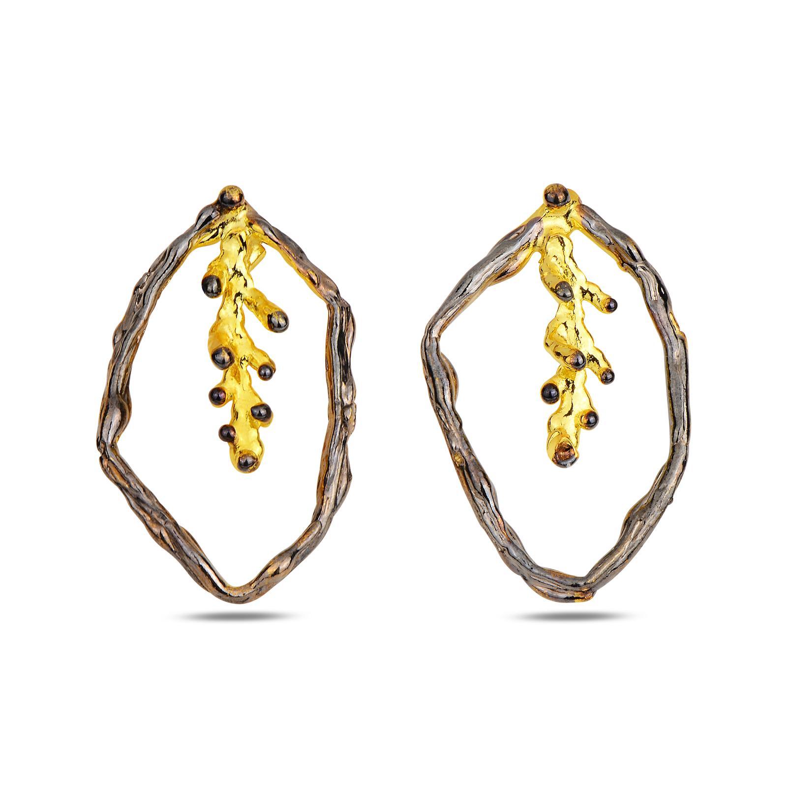 A pair of handcrafted two-tone earrings featuring a dark oxidized silver branch forming an outer hoop, with an 18K gold-plated pine twig dangling inside. Measuring 3.5 cm by 2 cm.