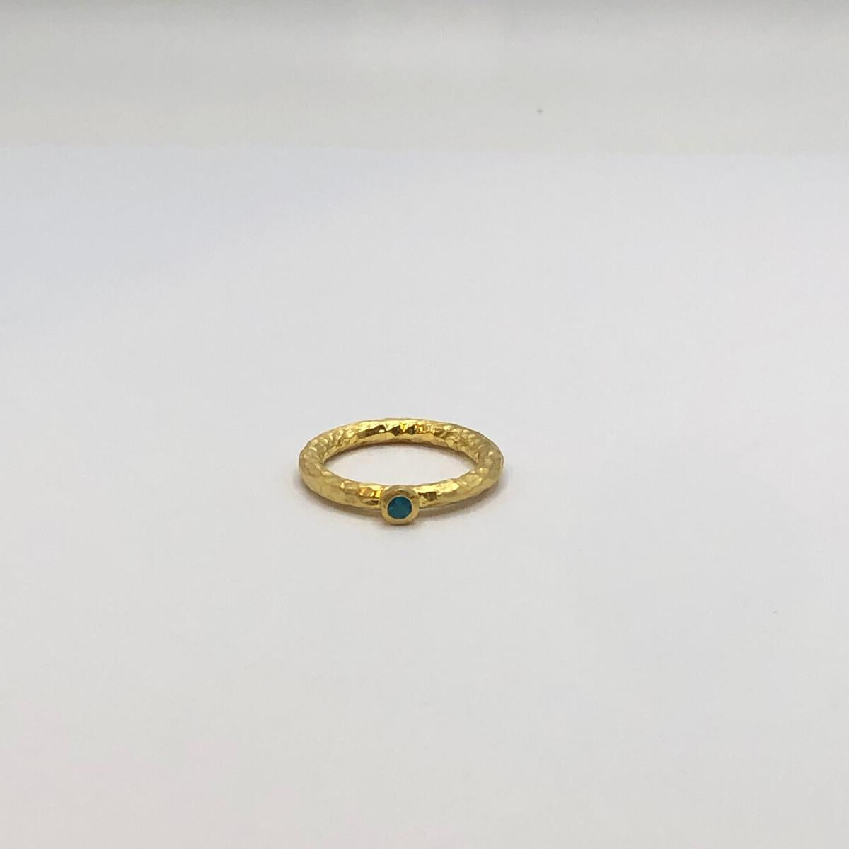 A handcrafted 18K gold-plated 925 sterling silver ring featuring an organic hammered texture and a genuine, vibrant natural blue topaz stone in a bezel setting.