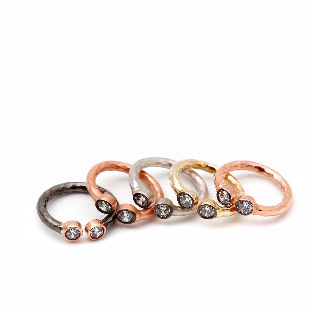 A collection of textured open cuff rings displaying different premium platings, including 18K gold, rose gold, and black rhodium, all accented with zircon stones.