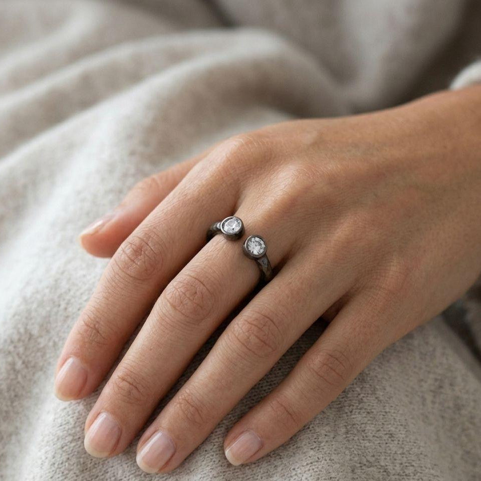A handcrafted adjustable open ring made of pure 999 fine silver. The textured band features two sparkling zircon stones at the tips, showcasing a stunning organic design.