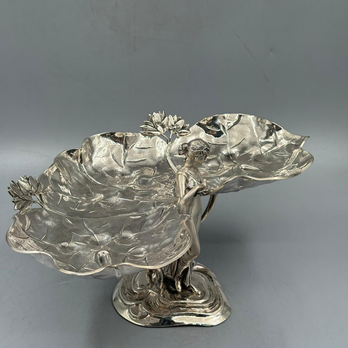 A detailed view of a silver Art Nouveau-style female figure at the base, supporting two lotus leaf-shaped trays with lotus flower accents.