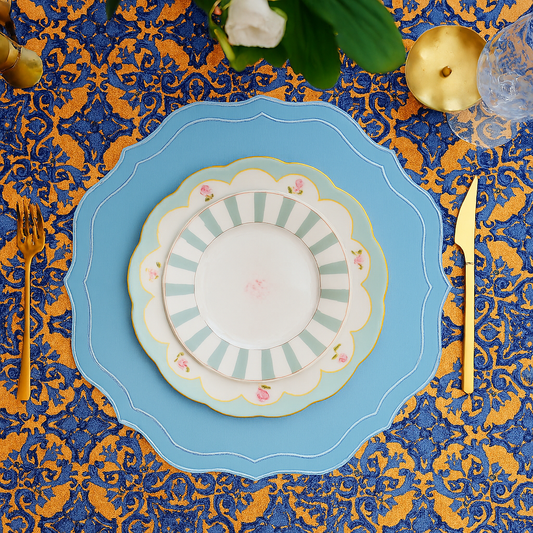 Orchid sky blue square faux leather placemat with subtle embroidery, styled with silver cutlery and a white ceramic plate on a minimalist dining table.