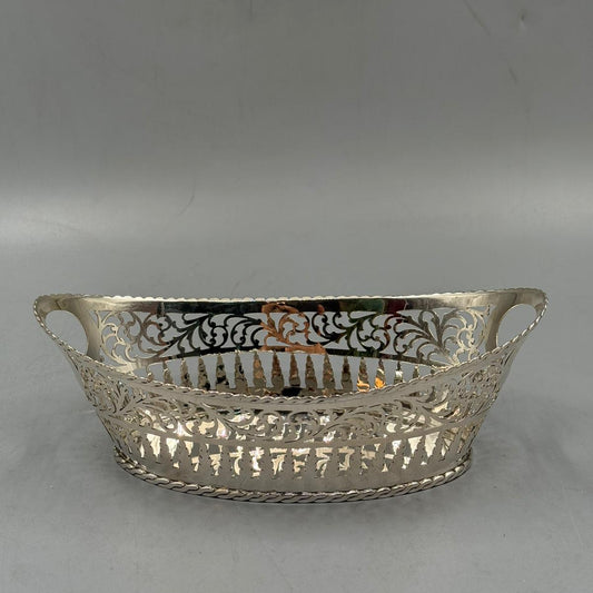 An antique silver serving tray in oval shape, featuring intricate cut-out floral patterns and a round side handle.