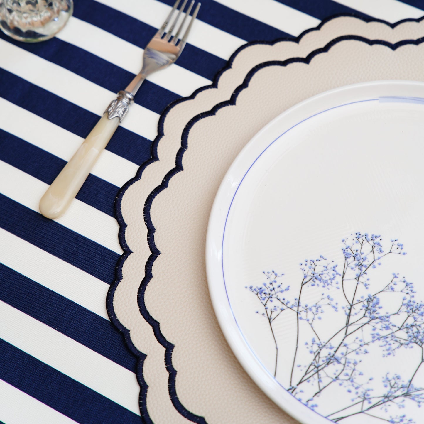 Scarlett White Navy Round Placemat – Skillfully handcrafted from eco-conscious faux leather, showcasing elegant navy detailing, double-layered protection, and stain resistance. A luxurious design from PNR Decor.