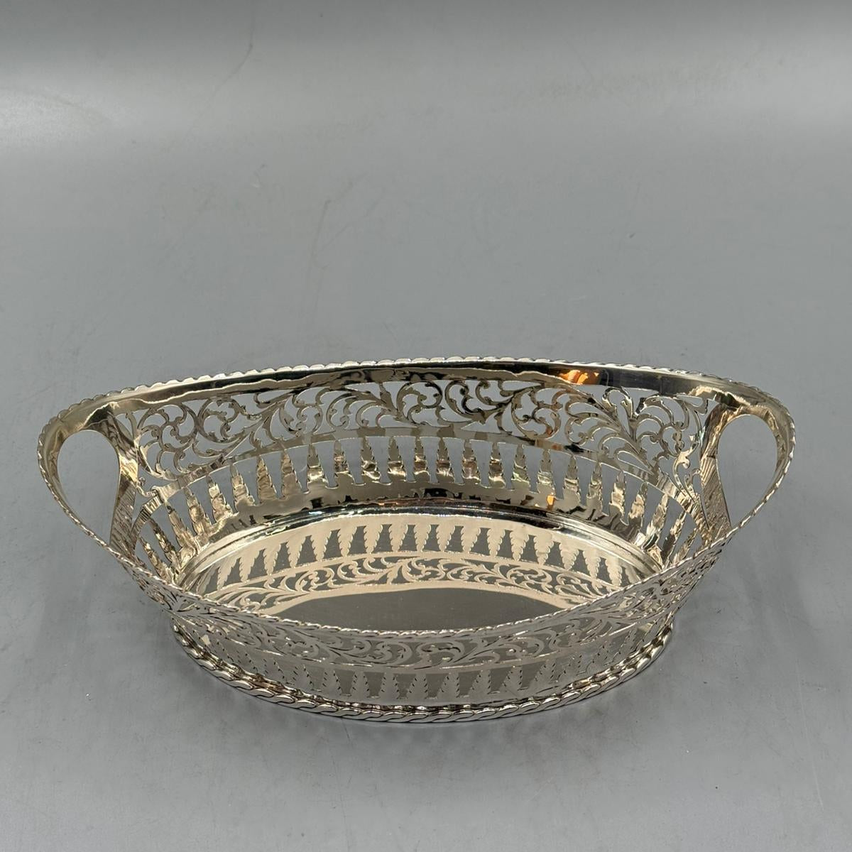 A classic silver oval serving tray featuring ornate cut-out designs and a shiny reflective finish.