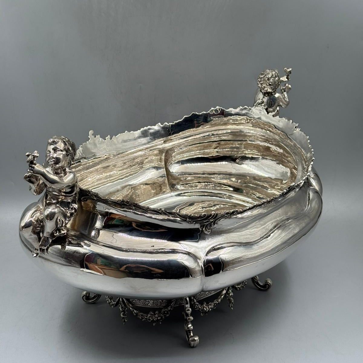 Angled view of ornate silver gondola centerpiece with putti