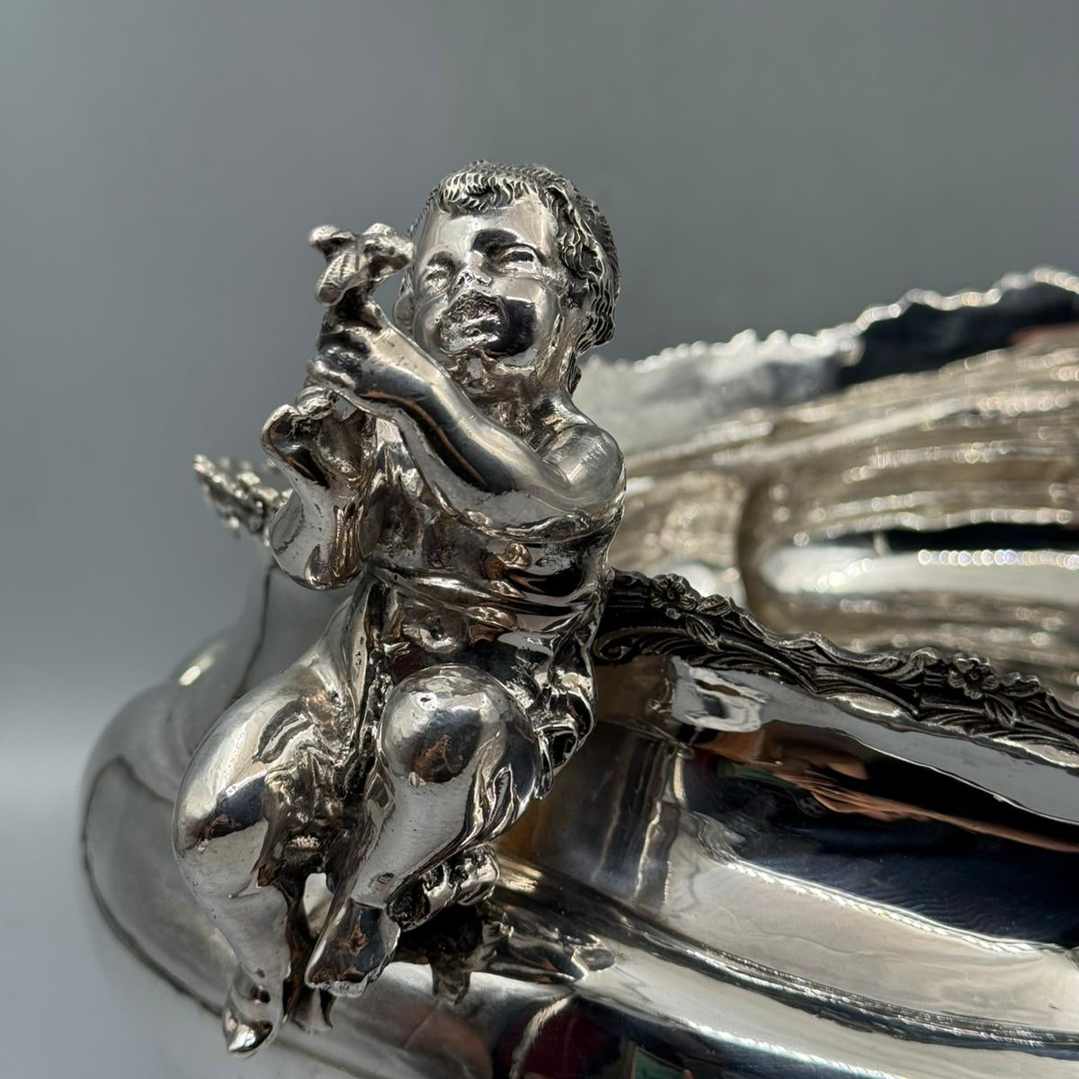 Close-up of cherub figure holding flower on antique silver gondola