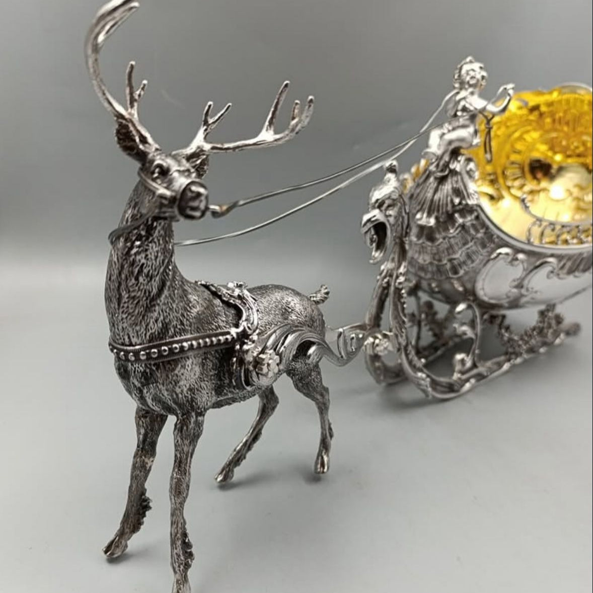 Close-up of antique silver reindeer pulling ornate gilded sleigh centerpiece