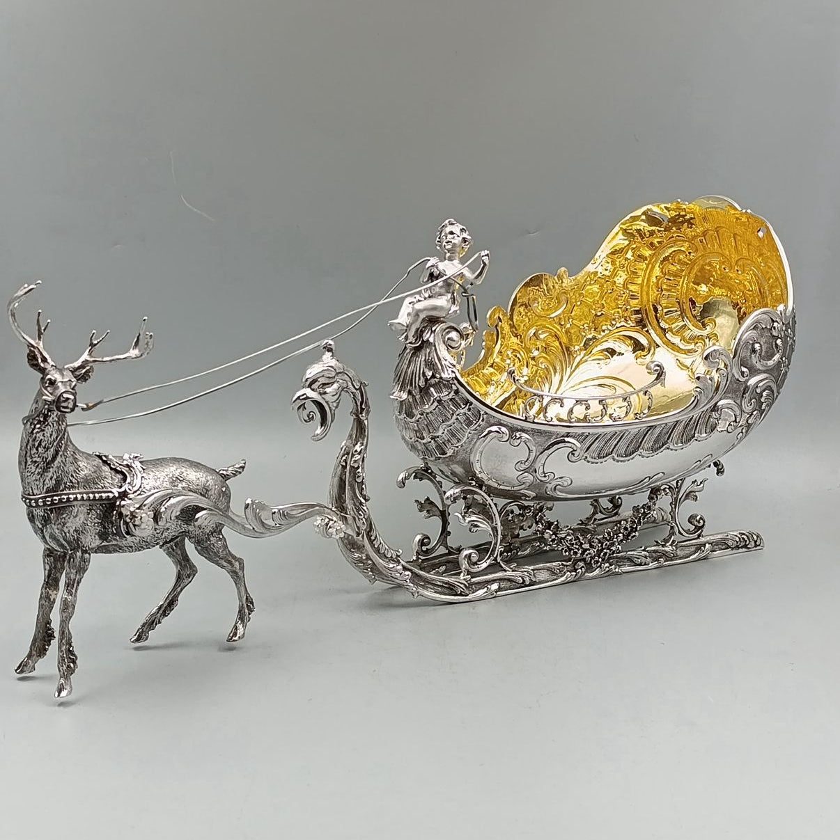 Front view of silver reindeer pulling antique gilded sleigh centerpiece