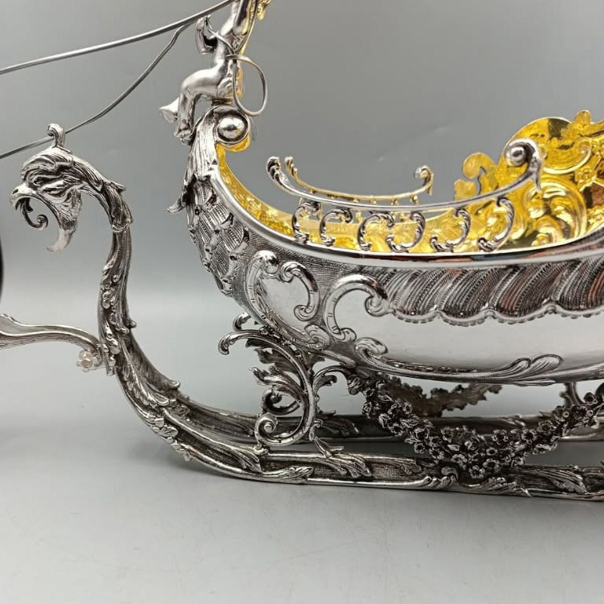 Side view of ornate antique silver sleigh with gilded interior