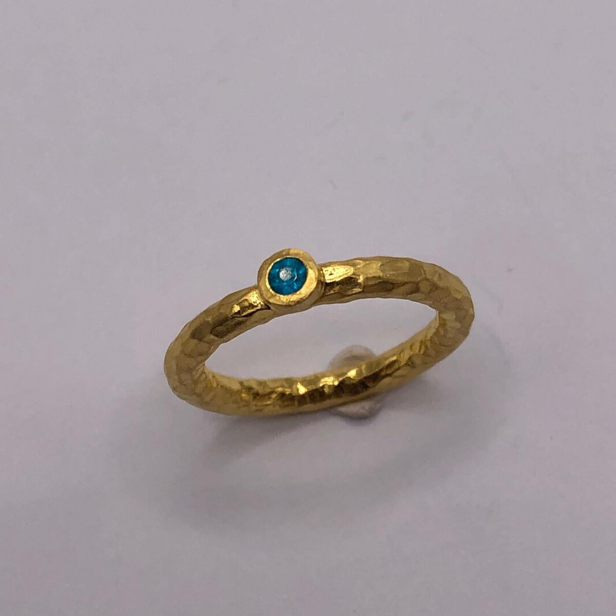Detailed focus on the delicate 3.5-gram 18K gold-plated ring, showing the stunning contrast between the rich gold finish and the genuine blue topaz centerpiece.