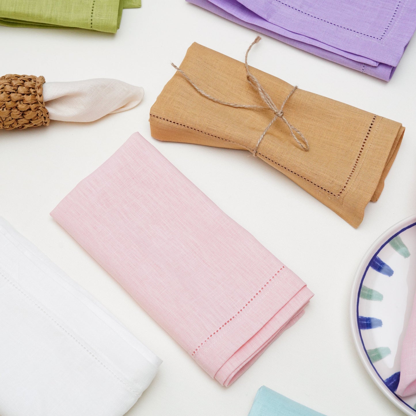 A shot highlighting the artisanal quality of the gold and pastel thread embroidery on a white napkin, contrasting with the rich texture of a navy velvet tablecloth in an upscale table setting.