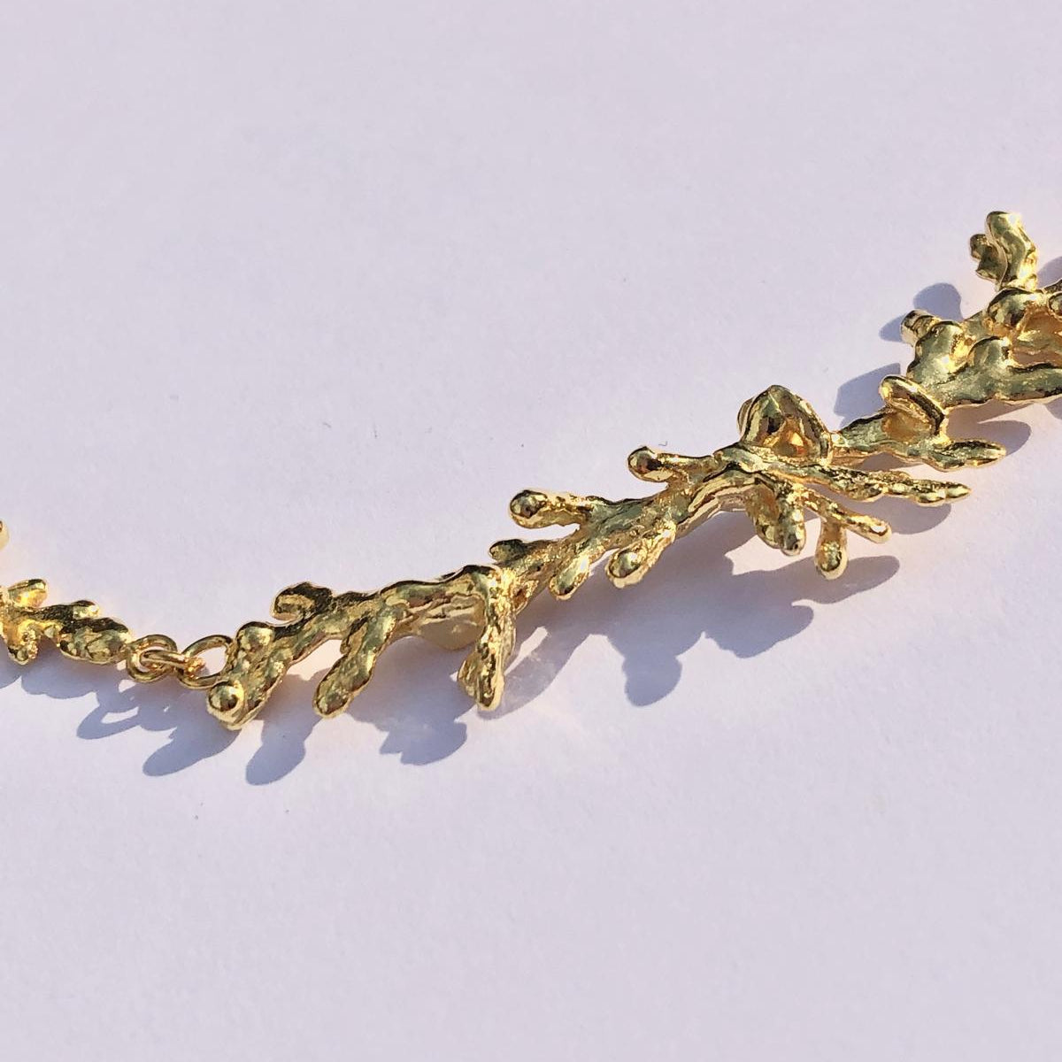 Lifestyle shot of a woman wearing the artisan-made gold-plated silver pine twig necklace, showcasing how the 42cm botanical design beautifully rests gracefully on the collarbone.