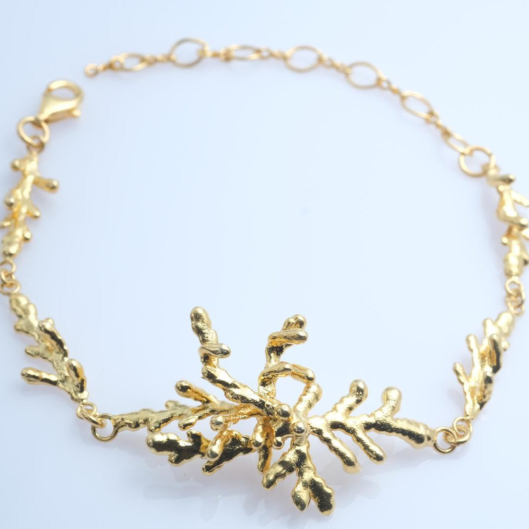 Angled shot showing the artisan-made gold-plated silver pine twig bracelet, highlighting its elegant drape and organic silhouette.