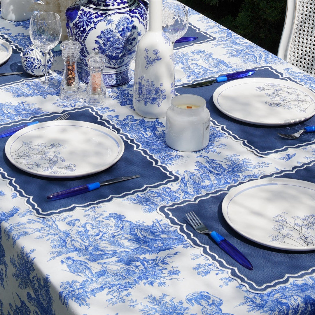 Full table view of a blue toile rectangular tablecloth set for a garden meal with coordinated dinnerware and linens