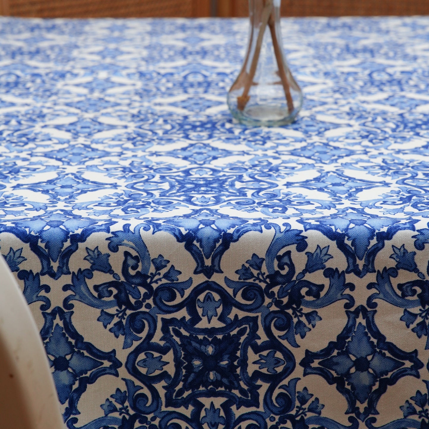 Blue and white damask rectangle tablecloth with a clear glass vase centerpiece in a warm, cozy dining setting