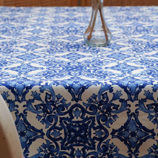 Blue and white damask rectangle tablecloth with a clear glass vase centerpiece in a warm, cozy dining setting
