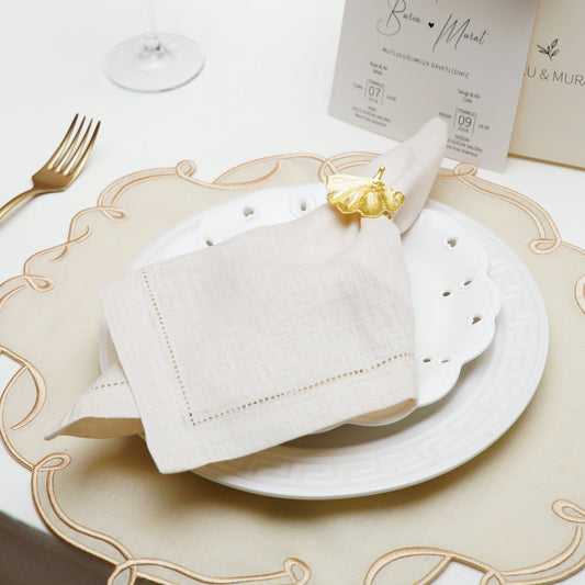 A close-up view of a premium white cloth napkin featuring a custom navy blue embroidered crest and a stylized initial W, suitable for elegant wedding table settings.