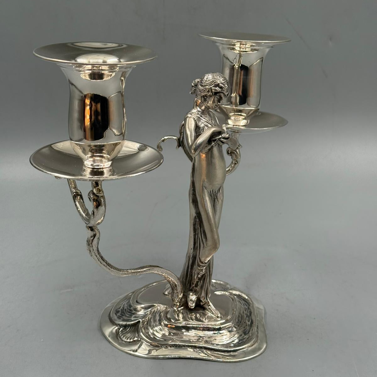 Decorative silver candlestick with two arms and a central female sculpture.