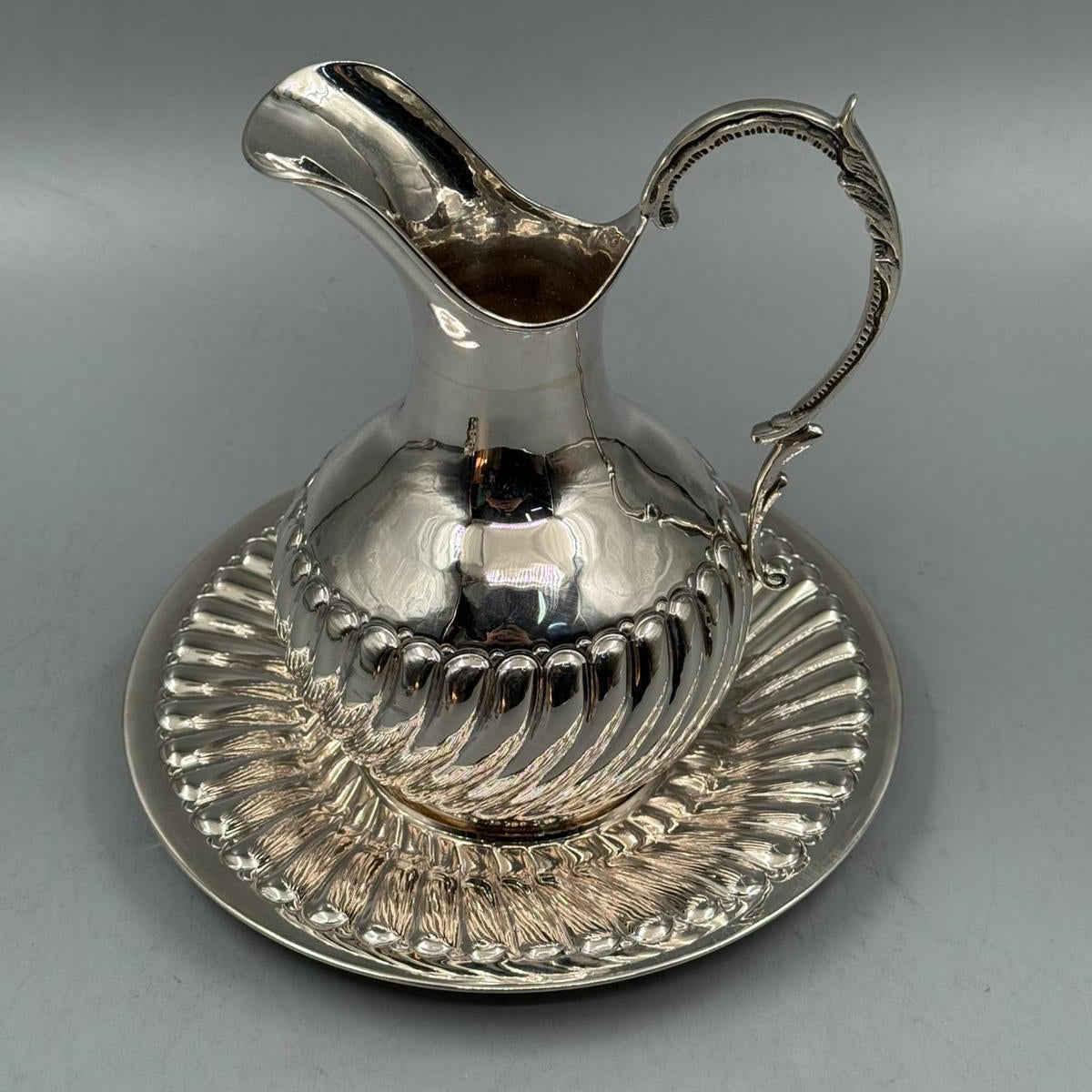 Decorative silver pitcher and plate set with embossed swirl design