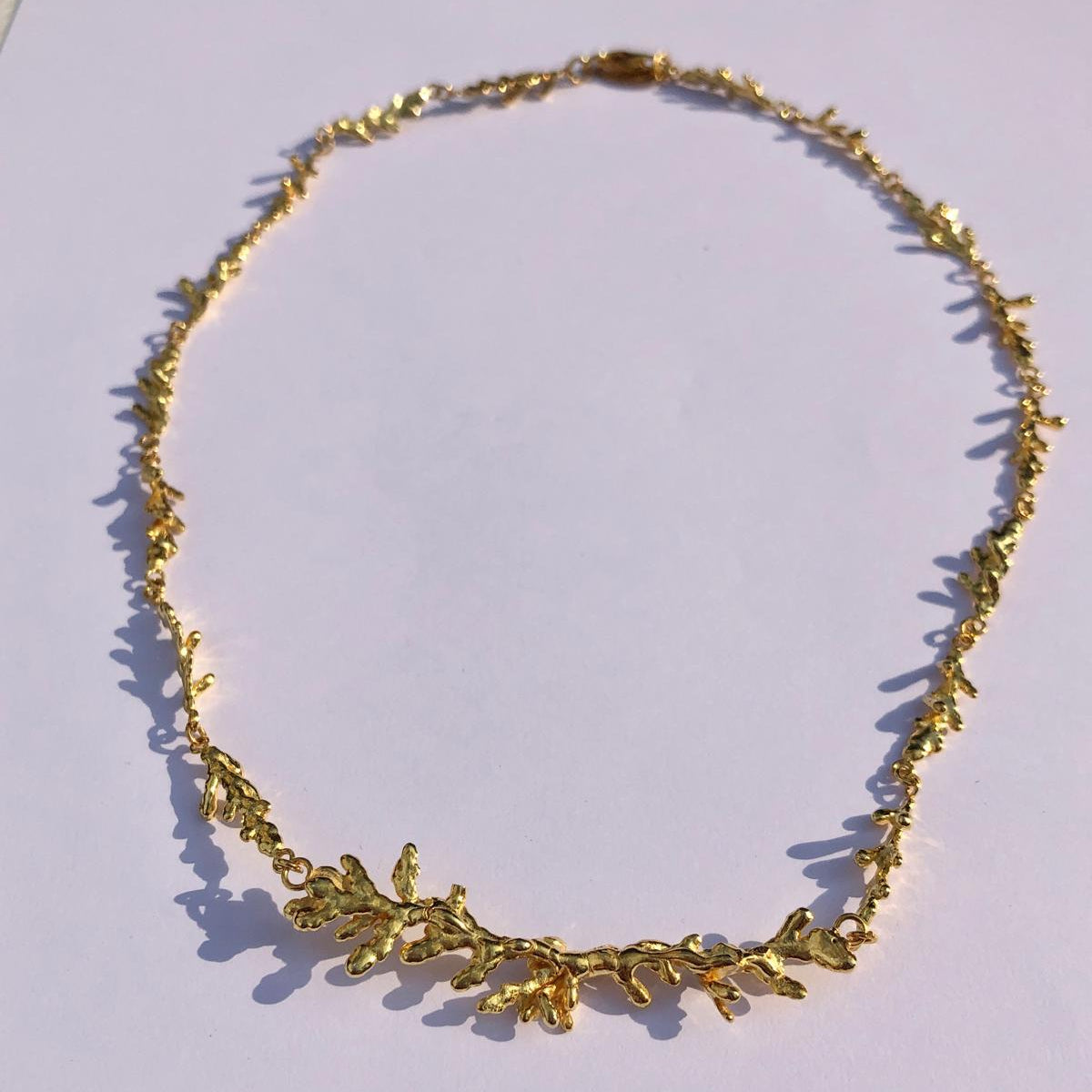 The 18K gold-plated pine leaf necklace displayed elegantly, highlighting the premium craftsmanship and the beautiful 17-gram solid silver base.