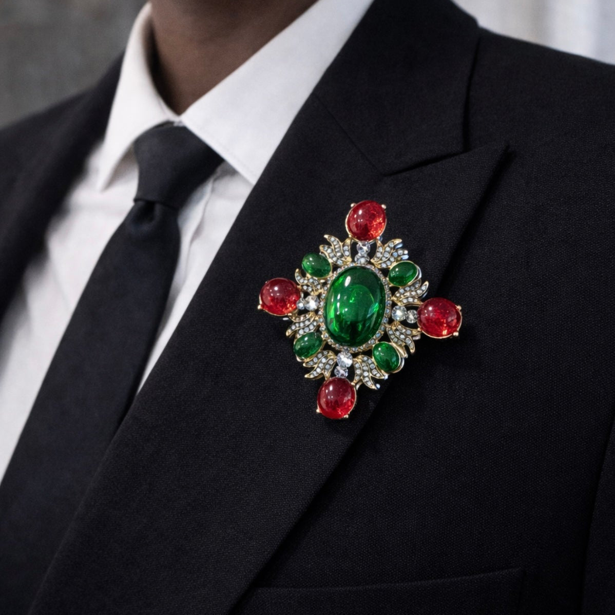 Close up of vintage style baroque cross brooch with green and red cabochon stones on black coat by PNR Decor ship from USA