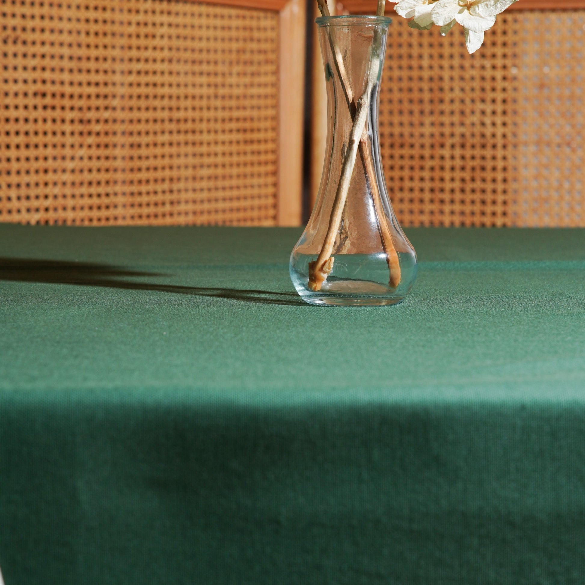 Forest green rectangular tablecloth styled with a clear glass vase and dried hydrangeas in warm natural light