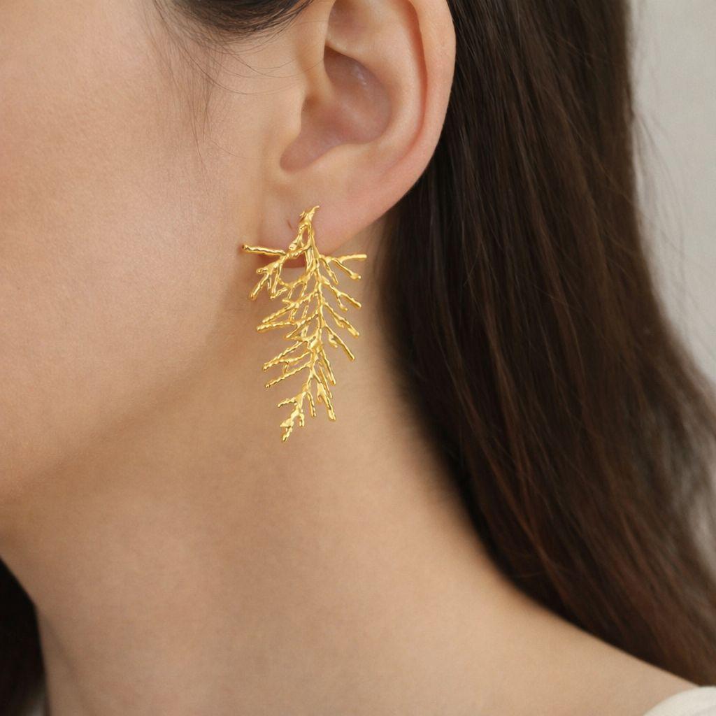 Close-up view of gold-plated silver leaf branch earrings, a nature-inspired jewelry design. These statement earrings feature intricate botanical details and a rich gold finish.