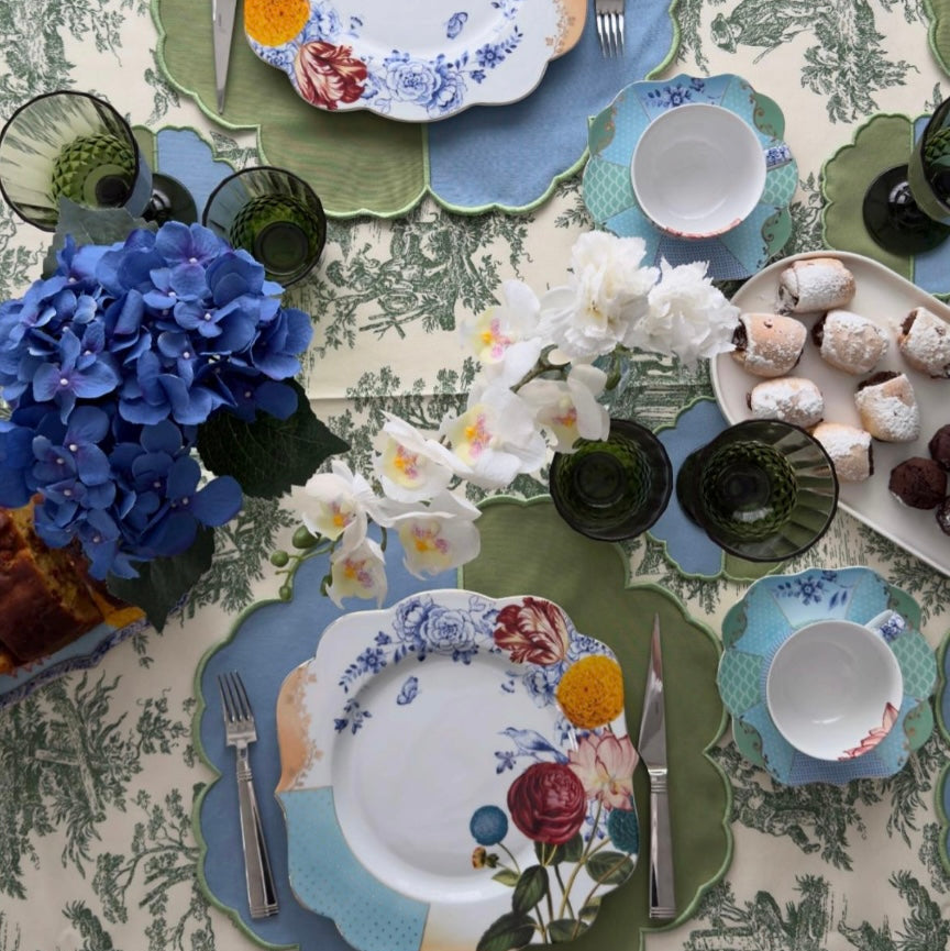 Close-up of the green toile pattern on the tablecloth, showing detailed countryside scenes on a white background