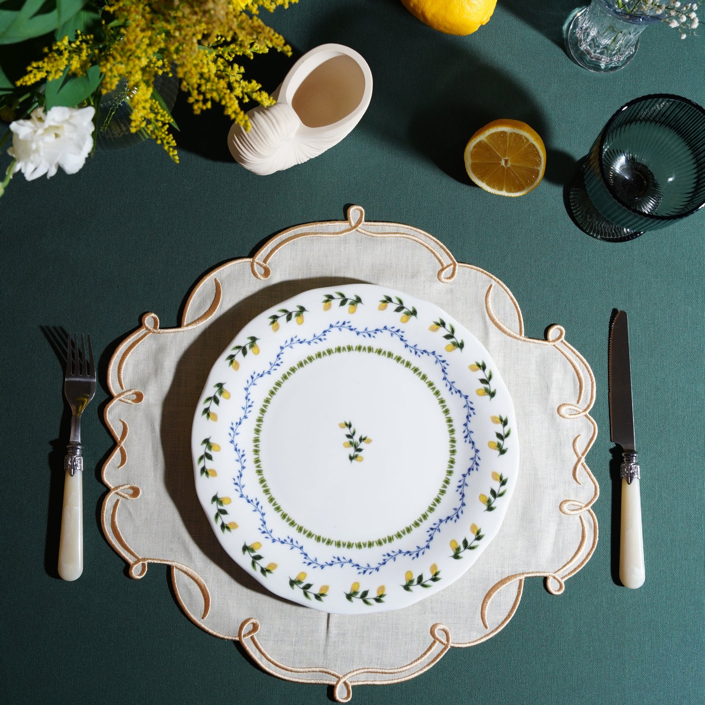 Ivory square placemat with gold trim styled on an elegant table