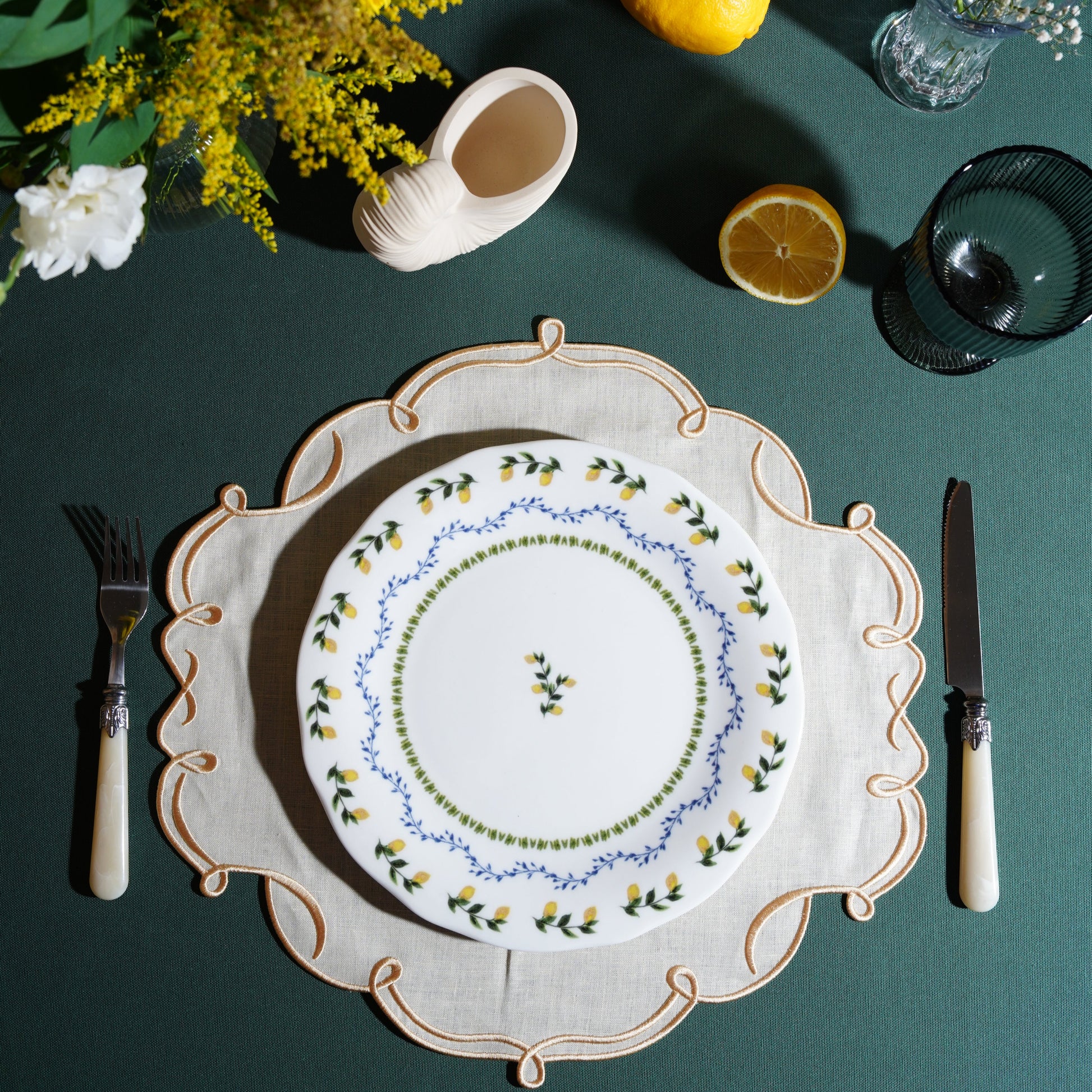 Ivory square placemat with gold trim styled on an elegant table
