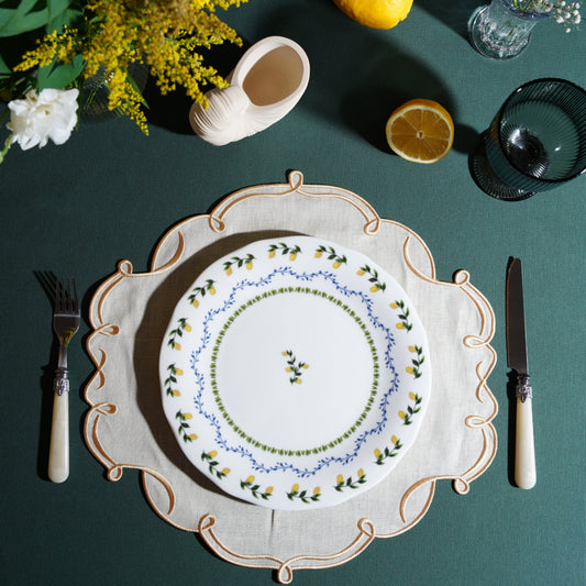 Ivory square placemat with gold trim styled on an elegant table