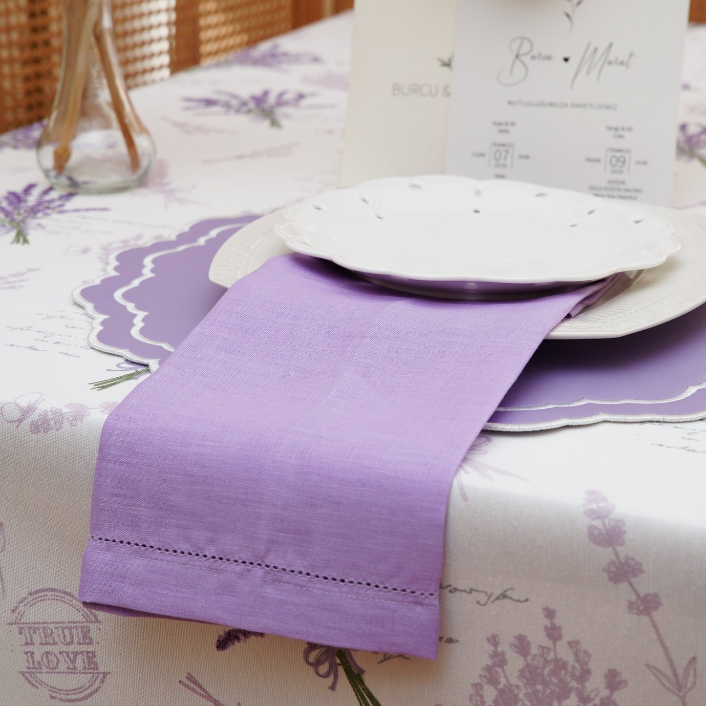 Top view of a botanical lavender tablecloth with scattered purple lavender sprigs on a clean white background