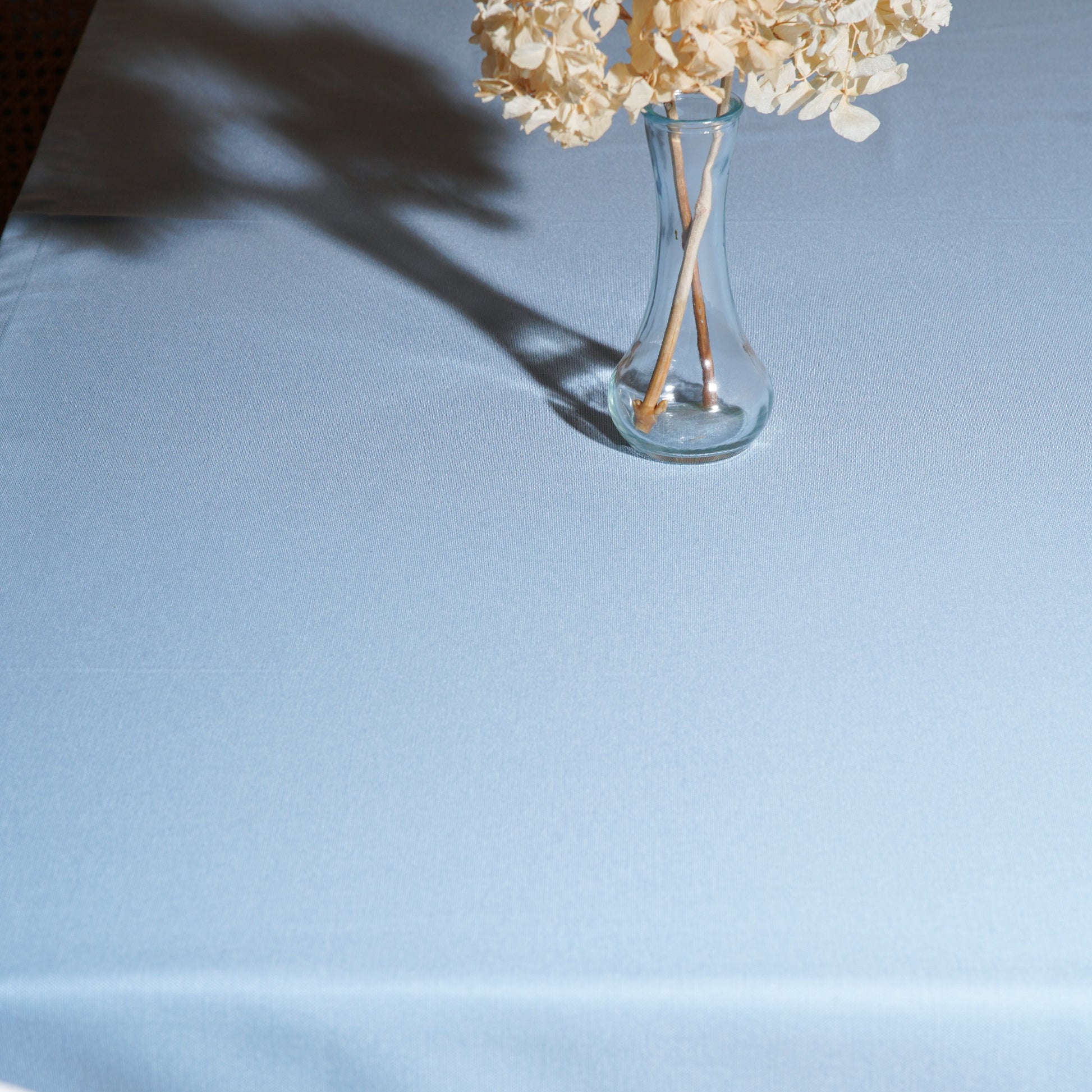 Light blue tablecloth draping over the table edge, showing the clean hem and fabric weave