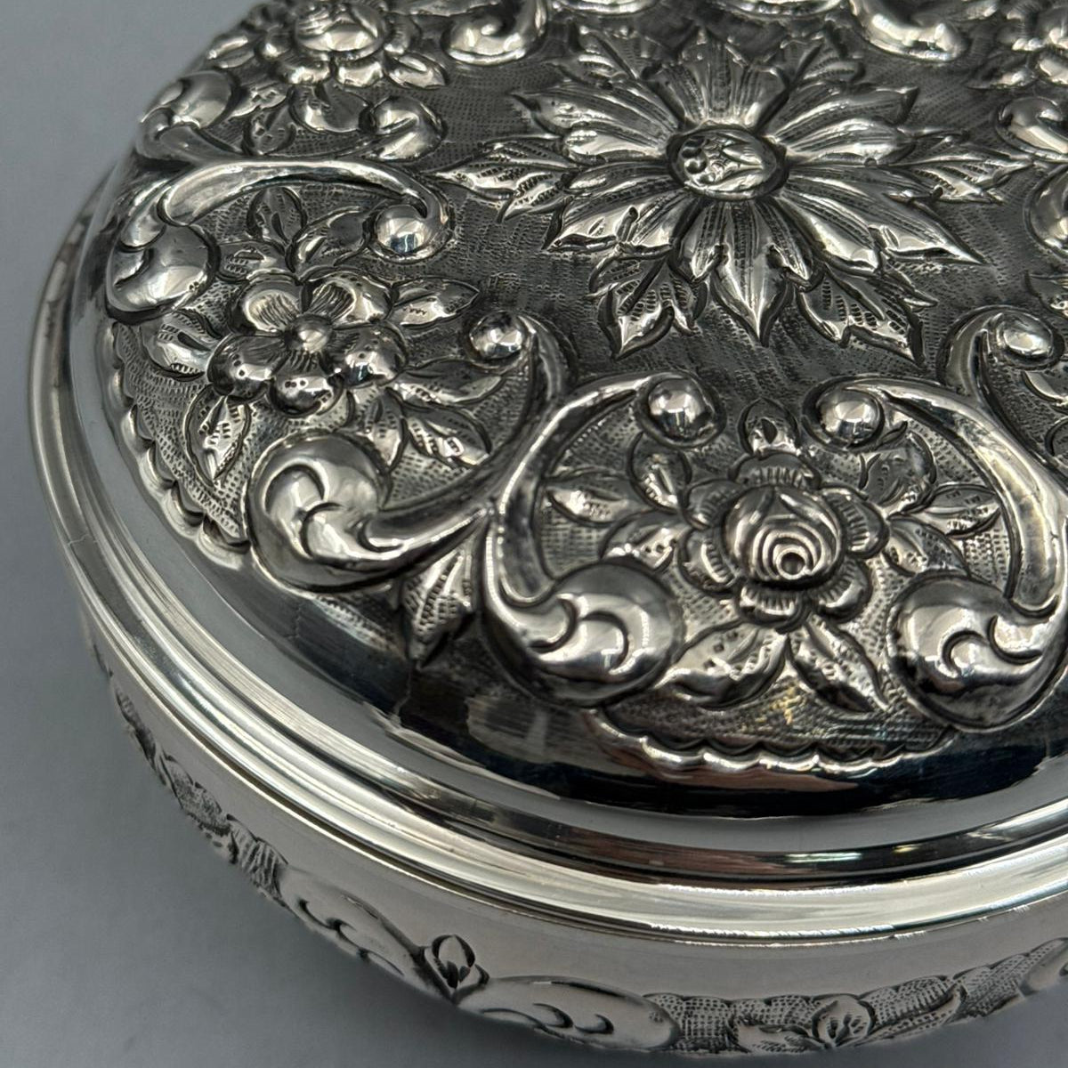 Front profile of the 13cm diameter triple-footed silver bonbonniere, showcasing the elegant elevation and continuous floral engraving patterns.