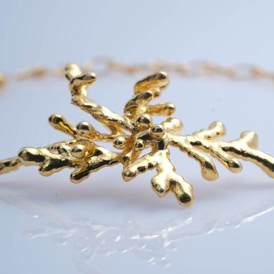 Detailed focus on the 3D clustered pine branch focal point of the handcrafted botanical bracelet, blending classic jewelry elegance with wild nature.