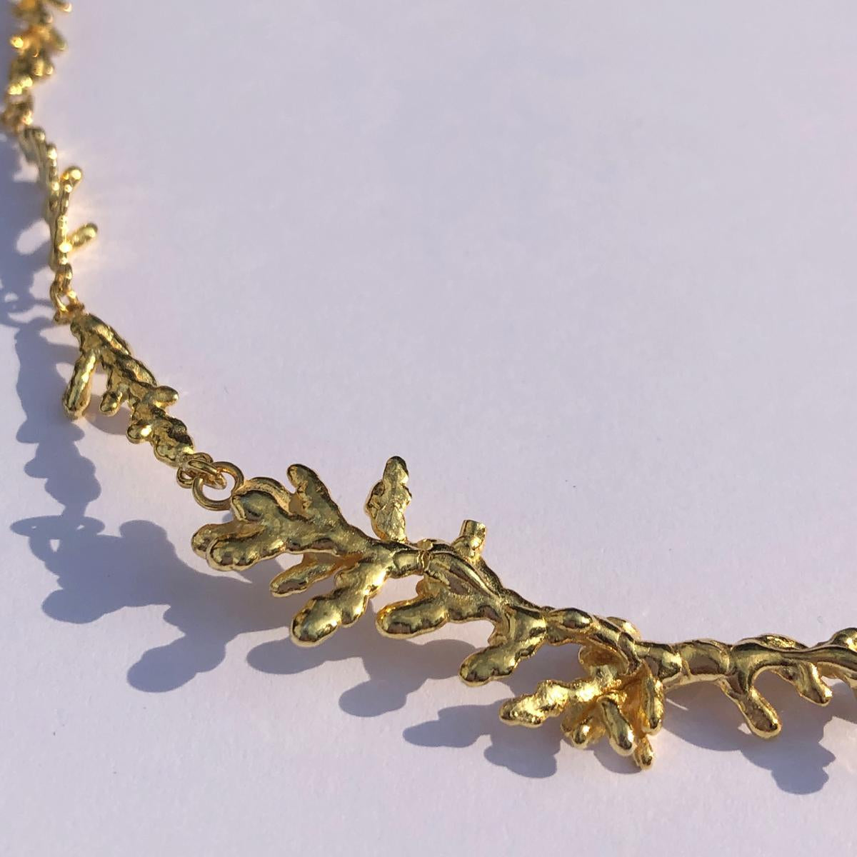 Detailed focus on the interlocking organic branch elements of the handcrafted botanical necklace, blending classic jewelry elegance with wild nature.