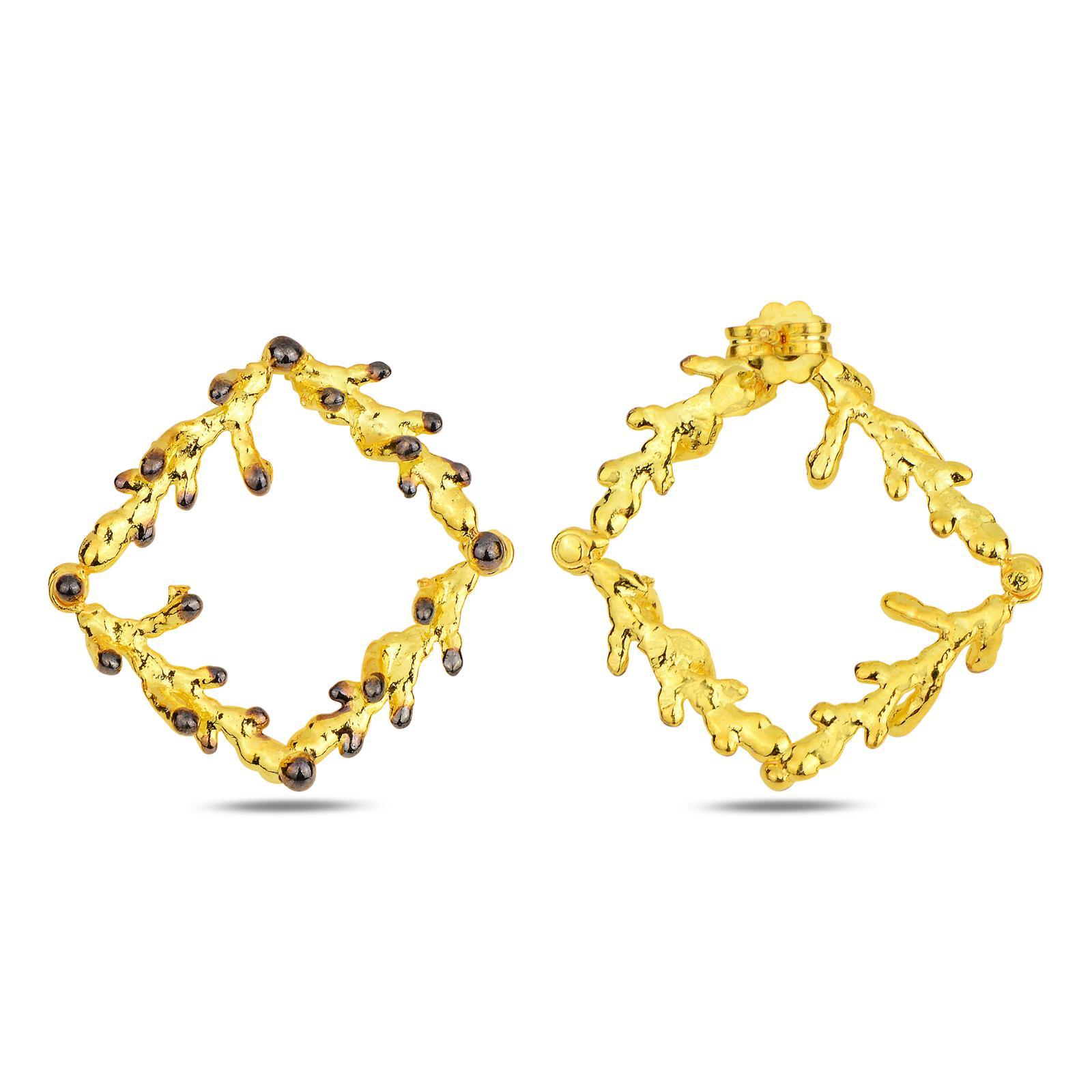 Close-up detail of the two-tone pine branch square earrings. The intricate wood texture of the gold-plated branches is highlighted by striking darkened, oxidized silver accents on the leaf nodes.