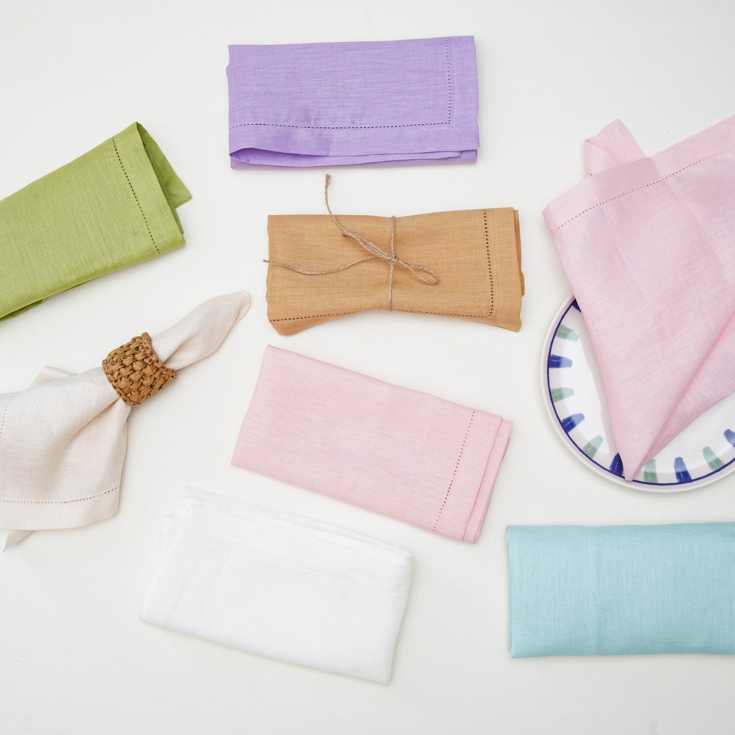 A fresh spring tablescape featuring soft pastel pink cloth napkins and scalloped placemats beneath classic white dining plates.