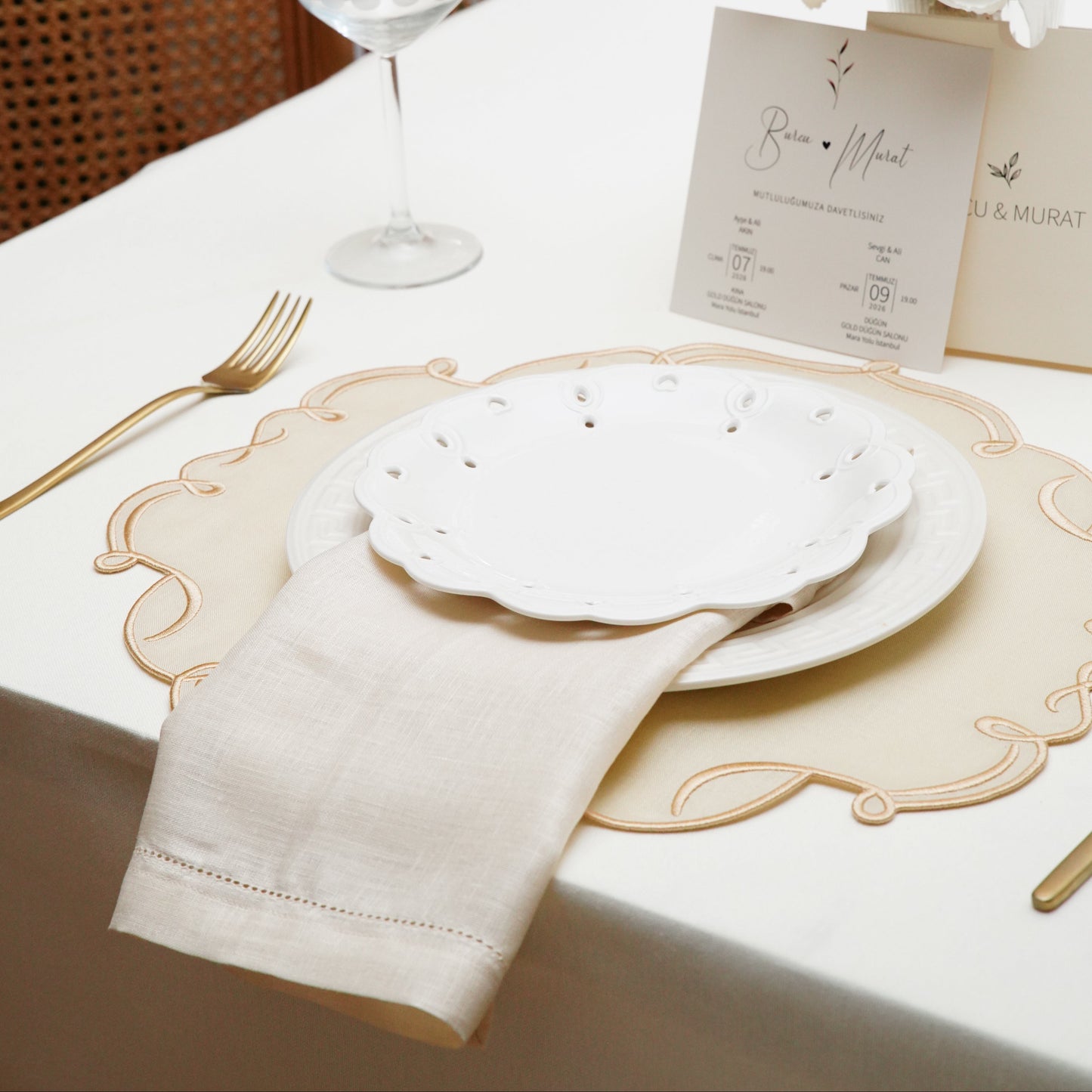 A detailed shot of a personalized white linen napkin with a navy blue embroidered monogram featuring an intricate crest around the letter W. A sophisticated addition to home dining.