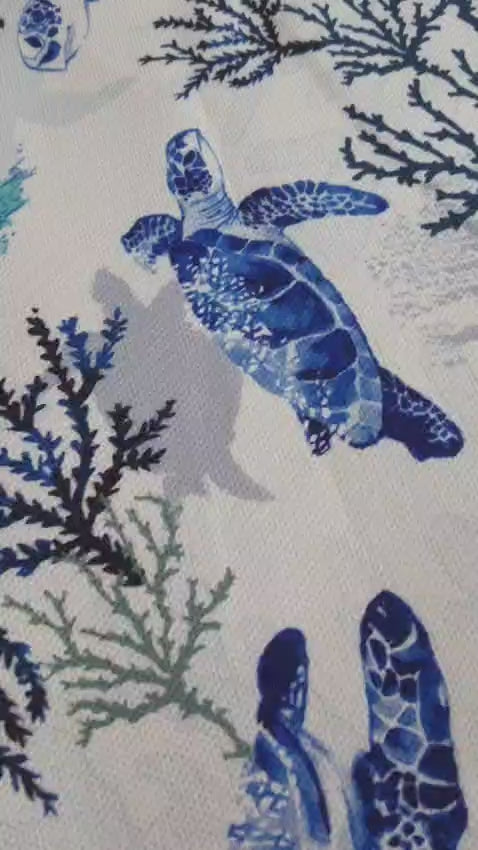 Close-up of the blue sea turtle print on the tablecloth with coral branches and ocean-inspired details