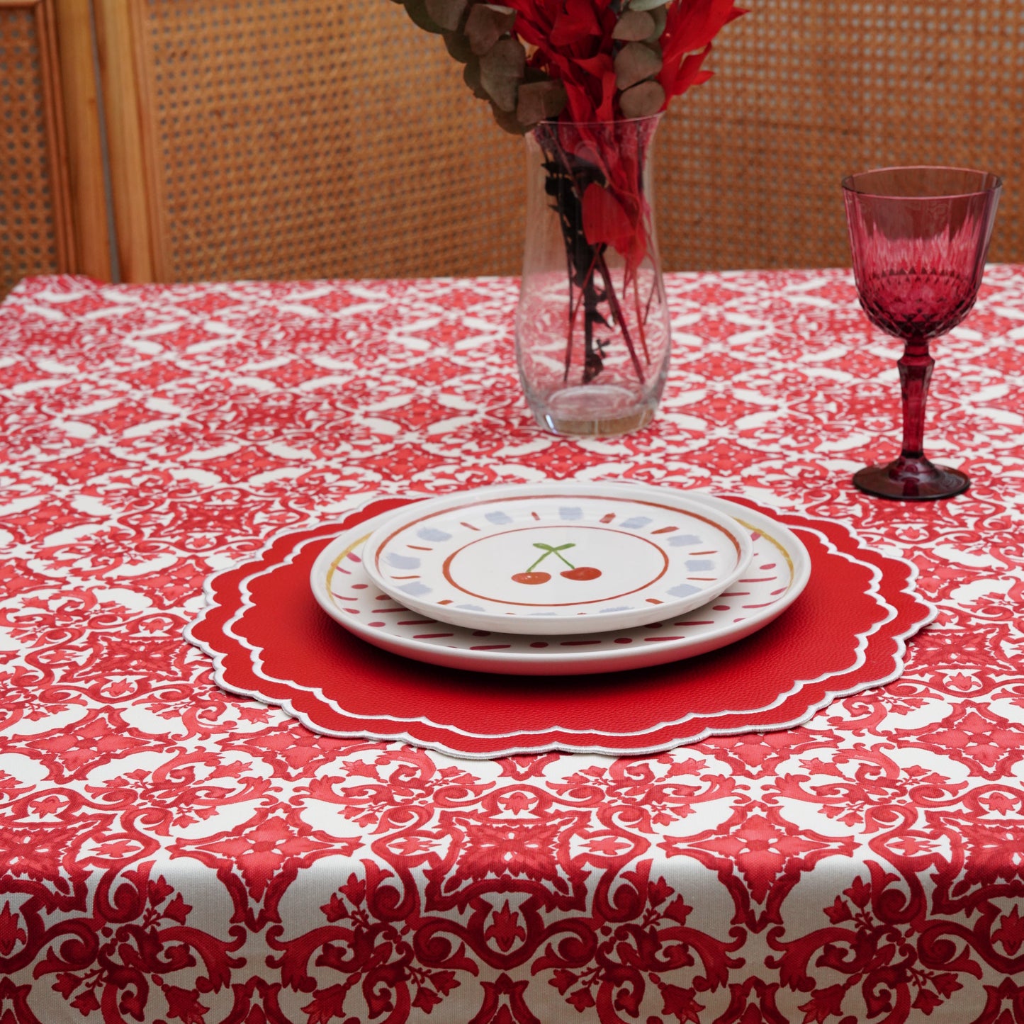 Red ornamental patterned tablecloth fabric detail showing crisp motifs and a textured weave.