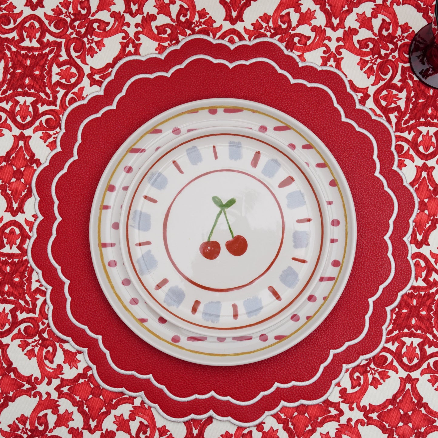 Red and white damask rectangular tablecloth draped over the table edge, highlighting the pattern and clean hem