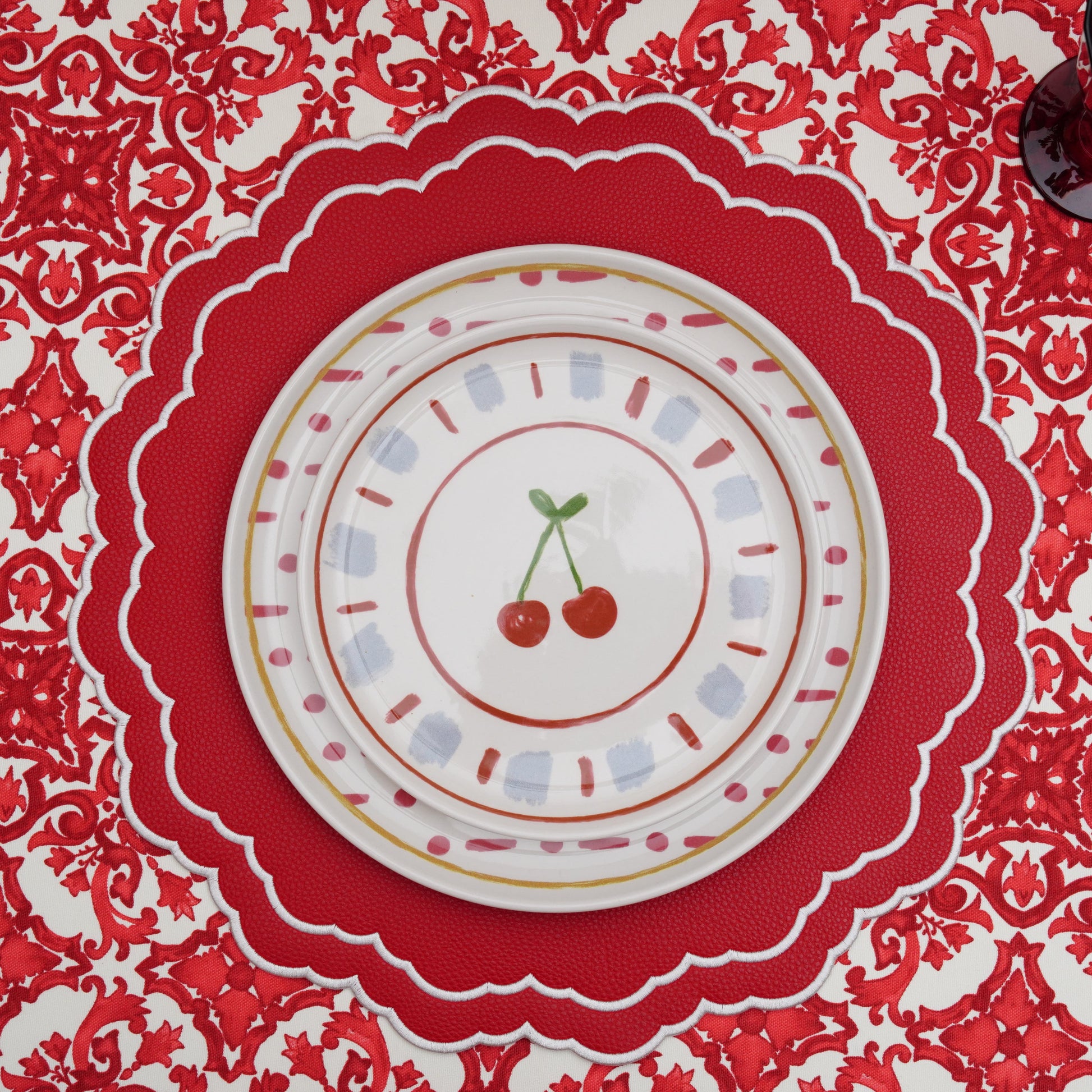 Red and white damask rectangular tablecloth draped over the table edge, highlighting the pattern and clean hem
