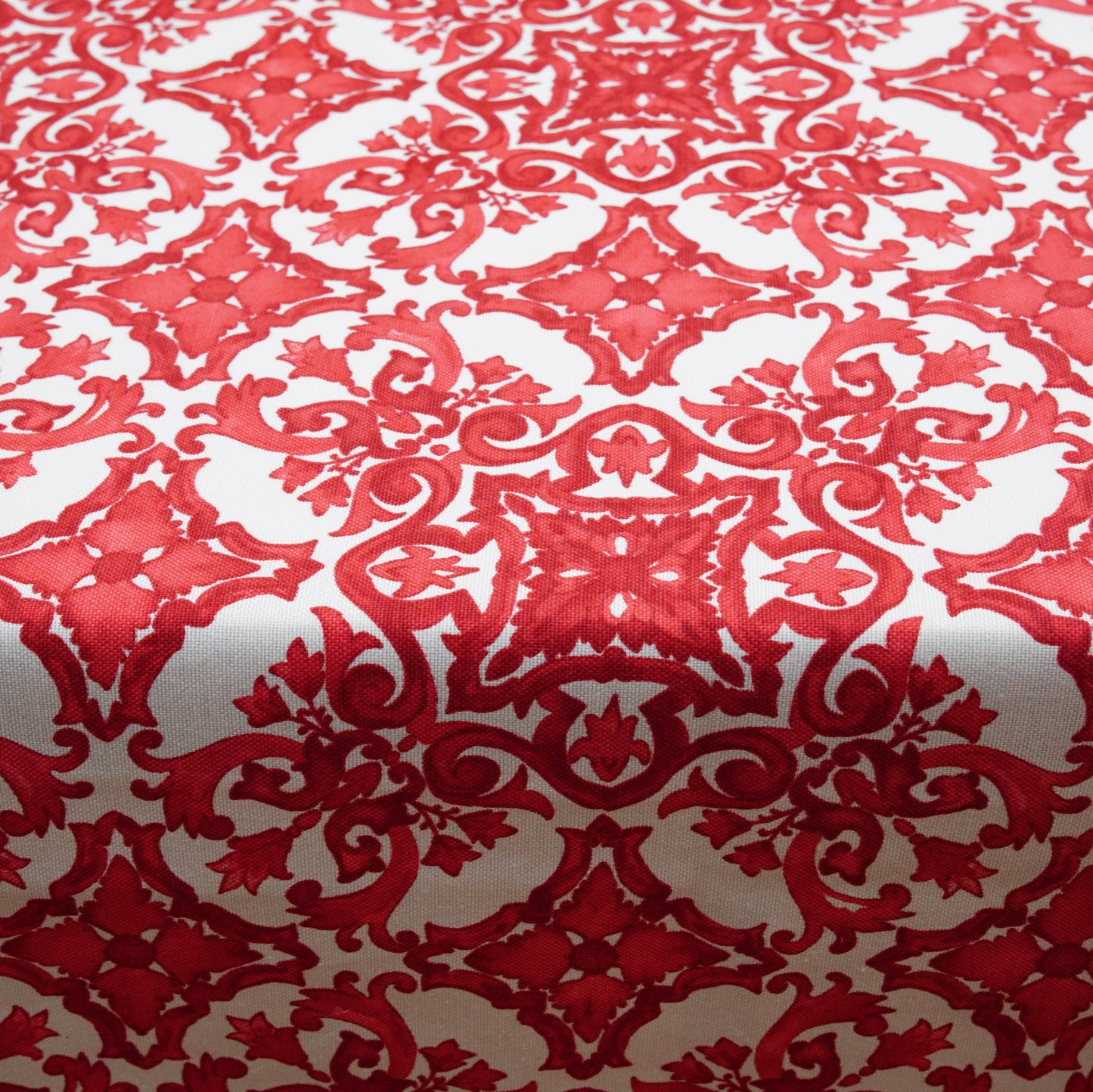 Close-up of a red and white damask tablecloth featuring an ornate ornamental pattern and woven texture